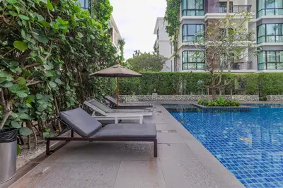a pool with two lounge chairs and an umbrella next to a building at C239 Best Spot Beachfront 1BR Near Top Beaches in Rawai Beach