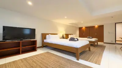 a bedroom with two beds and a flat screen tv at Tropical Poolside Villa - SGB4 in Phuket Town