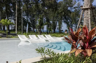 a swimming pool with white chairs in a park at Sunshine by Villacarte in Layan Beach