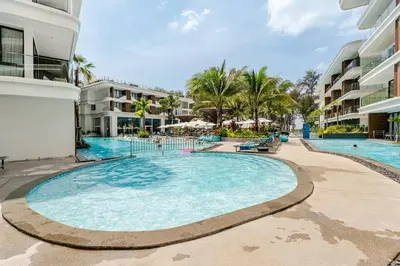 a large swimming pool in a resort with palm trees at Sunshine by Villacarte in Layan Beach