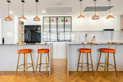 a kitchen with white cabinets and orange bar stools at Sunshine by Villacarte in Layan Beach
