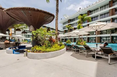 a resort with a pool and tables and umbrellas at Sunshine by Villacarte in Layan Beach