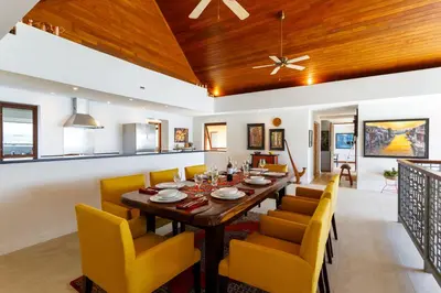 a dining room with a wooden table and yellow chairs at Seafront Pool Villa Nambo in Ko Taphao Noi