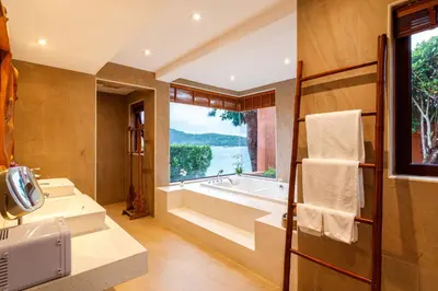 a bathroom with a tub and a large window at Seafront Pool Villa Nambo in Ko Taphao Noi