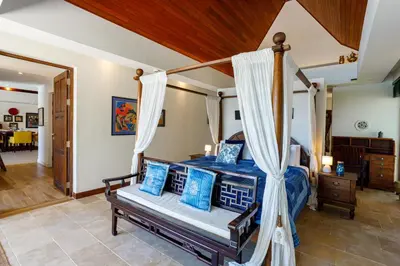 a bedroom with a canopy bed with blue pillows at Seafront Pool Villa Nambo in Ko Taphao Noi