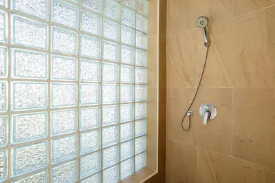 a shower with a glass block wall in a bathroom at Seafront Pool Villa Nambo in Ko Taphao Noi