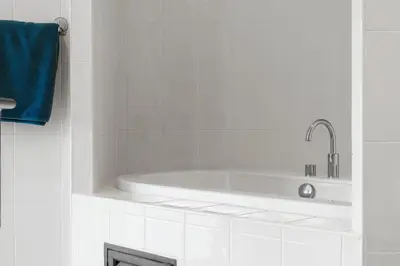 a white bathroom with a tub and a blue towel at Condominium Rawai D1 - near convenience beach, market, gym in Rawai Beach