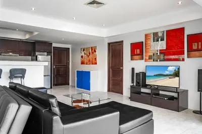 a living room with a black couch and a tv at Condominium Rawai D1 - near convenience beach, market, gym in Rawai Beach