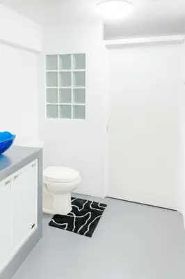 a white bathroom with a toilet and a rug at Chaota Modern House in Ban Ao Makham