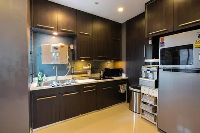 a kitchen with wooden cabinets and a stainless steel refrigerator at The Golden Palm Residence - Kathu - 10 min to Patong Beach in Kathu