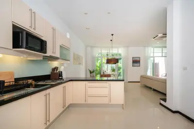 a kitchen with white cabinets and black counter tops at Private pool villa in the heart of Bangtao in Bang Tao Beach