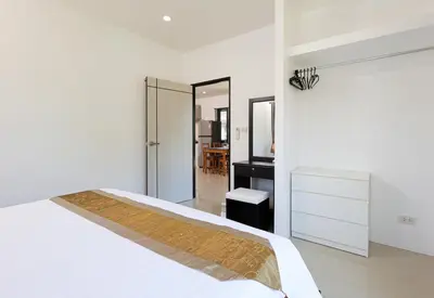 a white bedroom with a bed and a mirror at RinFin Beach House - Bangtao in Ban Thalat Choeng Thale