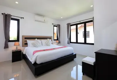 a white bedroom with a large bed and windows at RinFin Beach House - Bangtao in Ban Thalat Choeng Thale
