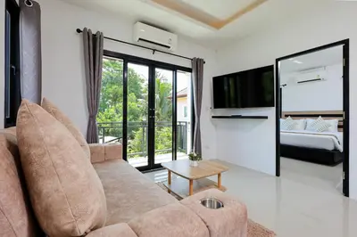 a living room with a couch and a bed at RinFin Beach House - Bangtao in Ban Thalat Choeng Thale