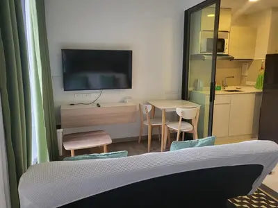 a living room with a table and a tv on the wall at Sky Park Laguna F4 in Laguna Phuket