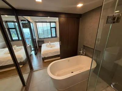 a bathroom with a bath tub and a bedroom at New 1BR Apartment in The Proud Karon Phuket in Karon Beach