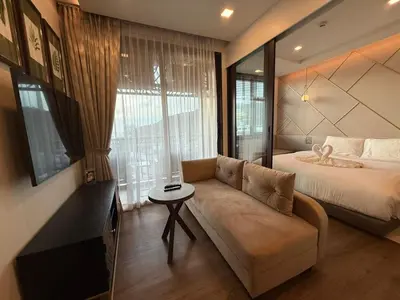 a bedroom with a couch and a bed and a window at New 1BR Apartment in The Proud Karon Phuket in Karon Beach