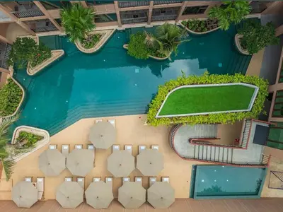 an aerial view of a swimming pool with chairs and a tennis court at New 1BR Apartment in The Proud Karon Phuket in Karon Beach