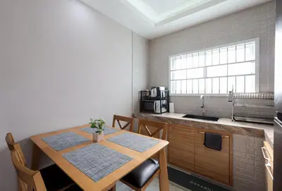 a kitchen with a wooden table with chairs and a sink at Leema Beach Villa - Bangtao in Ban Thalat Choeng Thale