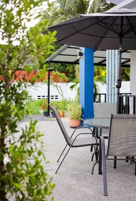 a table and chairs under an umbrella on a patio at Leema Beach Villa - Bangtao in Ban Thalat Choeng Thale