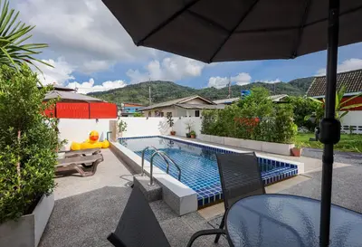 a swimming pool with a table and an umbrella at Leema Beach Villa - Bangtao in Ban Thalat Choeng Thale