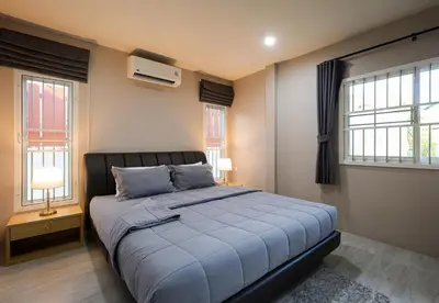 a bedroom with a large bed and two windows at Leema Beach Villa - Bangtao in Ban Thalat Choeng Thale