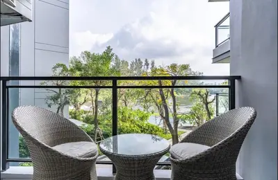 a glass table and two chairs on a balcony at Cassia 1 bedroom in Bang Tao Beach