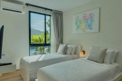 two white beds in a room with a window at Modern 1 & 2 Bedroom Apartments Naiyang Phuket by Mango Family in Nai Yang Beach