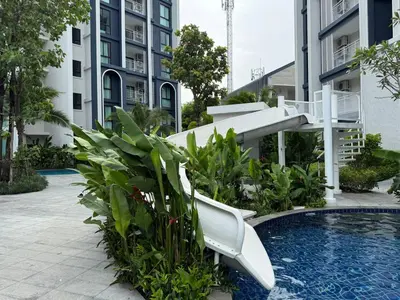a white chair sitting next to a swimming pool at Modern 1 & 2 Bedroom Apartments Naiyang Phuket by Mango Family in Nai Yang Beach