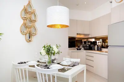 a white kitchen with a white table and chairs at Cassia Residences - 1BDR - Sea view in Laguna Phuket