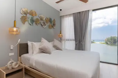 a bedroom with a large bed and a large window at Cassia Residences - 1BDR - Sea view in Laguna Phuket