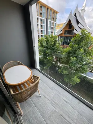 a balcony with a table and chairs and a large window at New luxury condo Ozone next to Laguna in Phuket