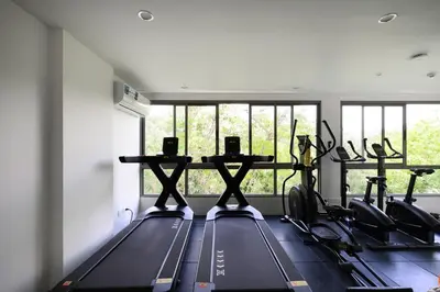 a gym with several treadmills and a row of windows at Fantasea Condo Kamala B708 1BDRM by Phuket Sabay Rent in Kamala Beach