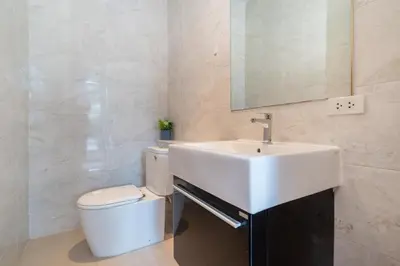 a white bathroom with a sink and a toilet at Mahogany Superb Pool Villa in Pasak in Phuket