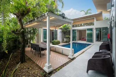 a house with a swimming pool and a dining area at Mahogany Superb Pool Villa in Pasak in Phuket