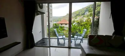 a living room with a view of a balcony with chairs at Chic B309 in Karon Beach