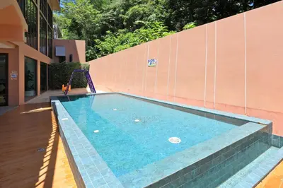 a swimming pool with a slide next to a building at Cozy 2BR Apartment in The Proud Karon Beach in Karon Beach