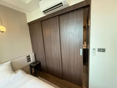 a bedroom with a wooden door and a bed at Cozy 2BR Apartment in The Proud Karon Beach in Karon Beach
