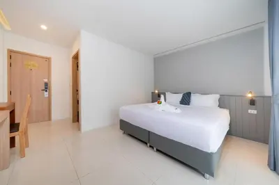 a bedroom with a large bed and a table and a room at Thawalai Inn Kata in Kata Beach