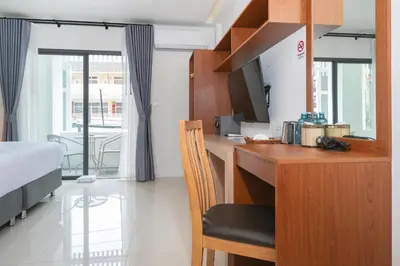 a room with a desk with a bed and a television at Thawalai Inn Kata in Kata Beach