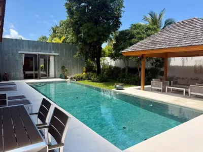 a swimming pool with chairs and a gazebo at Peaceful villa in the heart of the Anchan Tropicana project in Ban Phru Champa