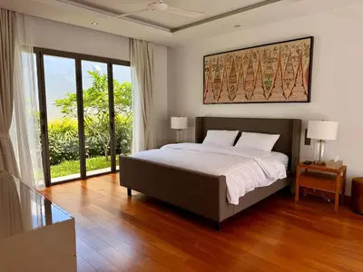 a bedroom with a large bed and a large window at Peaceful villa in the heart of the Anchan Tropicana project in Ban Phru Champa