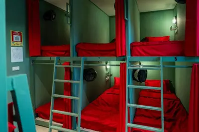three bunk beds in a room with red sheets at Whoopers Hostel Ao Nang - By The Beach in Ban Khlong Haeng