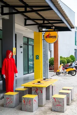 a person standing next to a table in front of a building at Whoopers Hostel Ao Nang - By The Beach in Ban Khlong Haeng