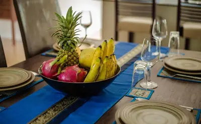 a bowl of fruit on a table with plates and glasses at Villa Vie Phuket Rawai 3 Bedrooms in Ban Saiyuan (1)