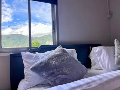 a bedroom with a bed with pillows and a window at Ali House Patong in Patong Beach