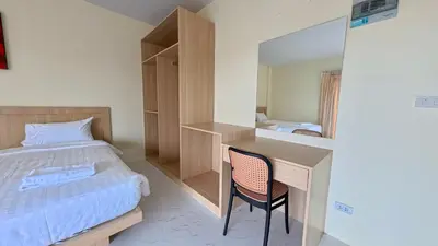a bedroom with a bed and a desk with a chair at Baan Phu Chalong Place in Ban Suan
