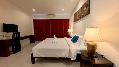 a hotel room with a bed and a red curtain at Baan Phu Chalong Place in Ban Suan