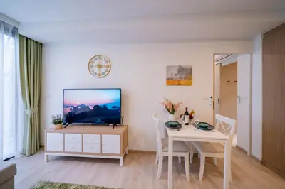 a living room with a table and a television on a white wall at Sky park 2 bedroom 60m2 in Laguna Phuket