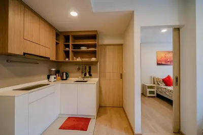a kitchen with white cabinets and a living room at Sky park 2 bedroom 60m2 in Laguna Phuket